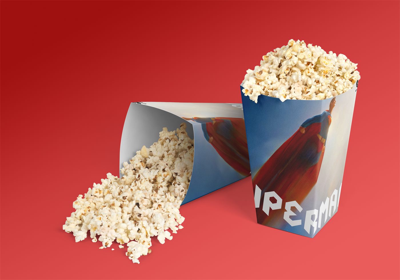 Superman branded popcorn box overflowing with popcorn on a red background